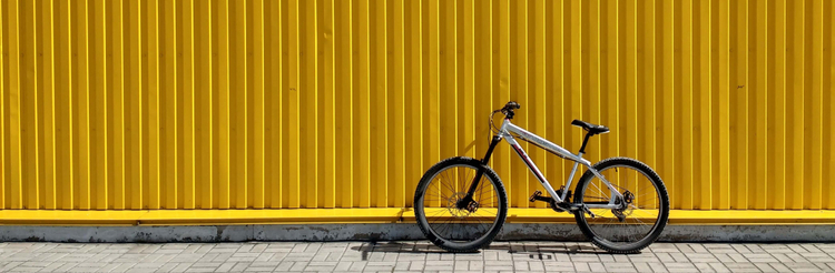 A bike leaning against a yellow wall, decorative image.